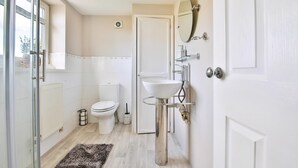 A bathroom with a toilet, sink, mirror, and a glass shower enclosure.