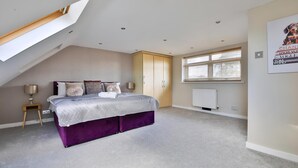 A bedroom with a bed, a nightstand, a wardrobe, a window, and a radiator.