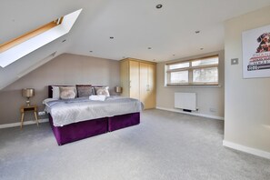 A bedroom with a bed, a nightstand, a wardrobe, a window, and a radiator.