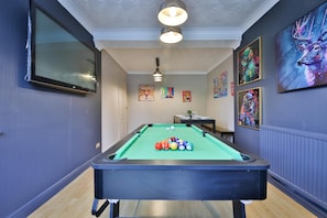 A pool table with balls, a ceiling light, and wall art. - Spacious Three-bedroom Home With Pool Table (Cardiff)