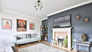 Una sala de estar moderna con un sofá gris, una chimenea y decoración en la pared.