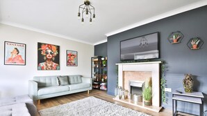 A living room with a grey sofa, a fireplace, and wall-mounted artwork.