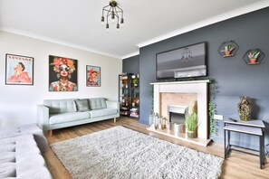 A living room with a grey sofa, a fireplace, and wall-mounted artwork.