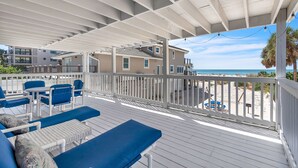 A covered outdoor deck with blue furniture, white railings, and a view of the beach. - ☀Beachfront🌴Full Property🍹Walk to John's Pass🌊John's Pass-Time Beach Cottages (Madeira Beach)
