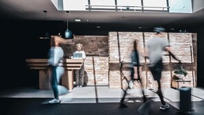 A modern lobby with a stone wall, a reception desk, and a large window. - Hotel Edelweiss (Gerlos)