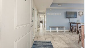 A hallway with a bench, a TV, and a clock on the wall. - Ocean View l 5BR l Pool l Sleeps 16 l Luxury Villa (N. Myrtle Beach)