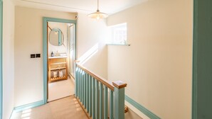 Un escalier avec une rampe en bois et un luminaire placé au-dessus.