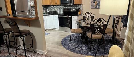 Una cocina moderna con armarios de madera, electrodomésticos de acero inoxidable y un comedor con una mesa redonda y sillas.