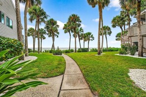 A pathway leading to a building surrounded by palm trees and a clear sky.