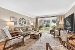 Ein geräumiges Wohnzimmer mit einer Couch, Sesseln, einem Couchtisch und einem Fernseher.