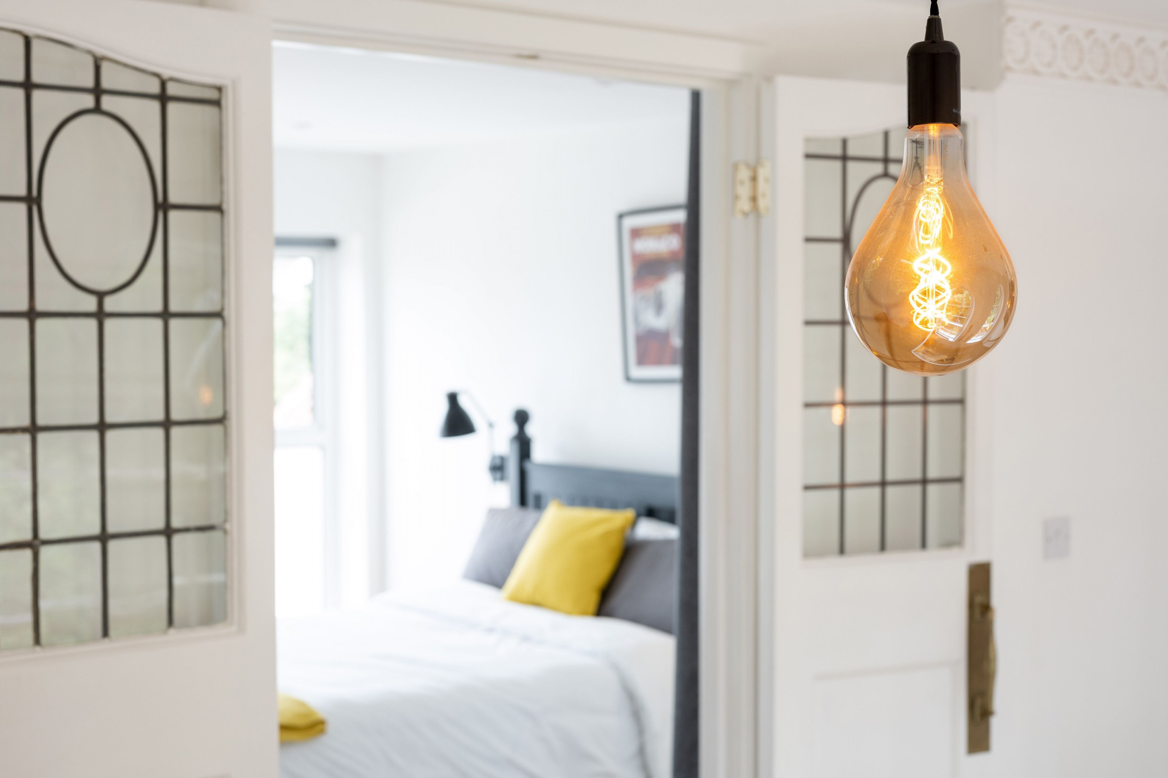 A modern bedroom with a bed, a nightstand, and a wall-mounted light fixture.