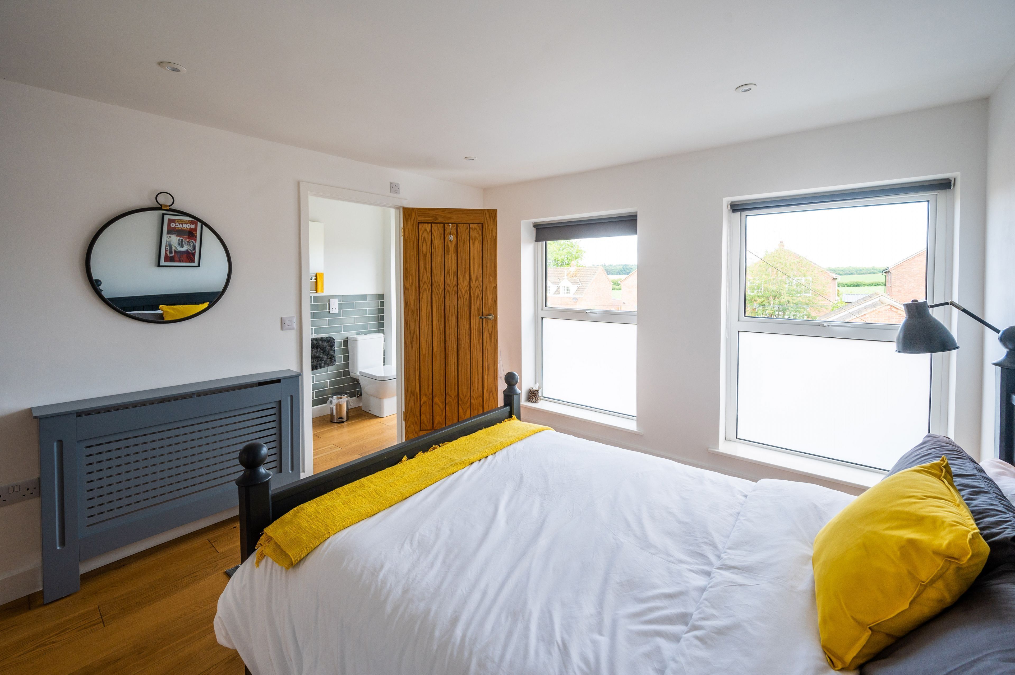 A bedroom with a bed, a window, a door, and a mirror.