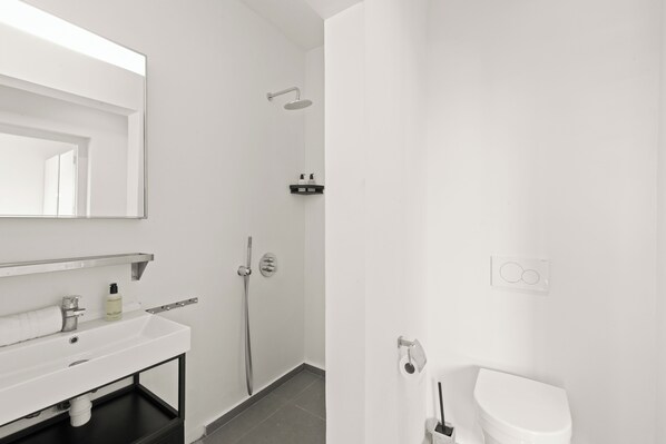 A modern bathroom with a white sink, mirror, and toilet.