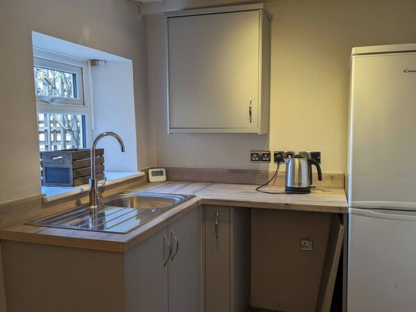 A compact kitchen with a sink, a kettle, and a refrigerator. - Cosy Cottage in Beautiful Masham (Ripon)