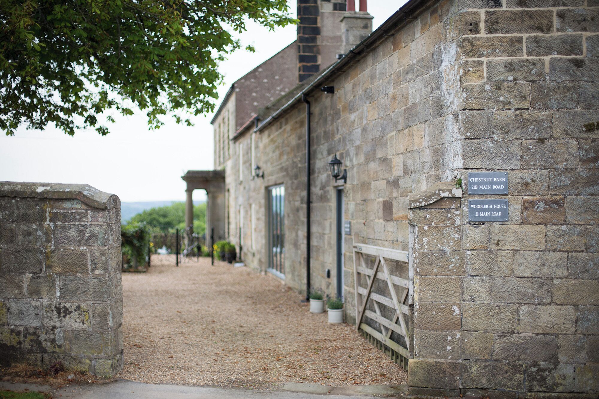 A stone building with signs for Chestnut Barn and Woodleigh House on Main Road.