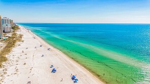 Una playa con agua turquesa cristalina, orilla de arena y varias sombrillas azules.
