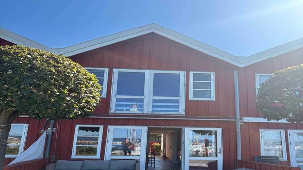 A two-story building with a red exterior, large windows, and a covered outdoor seating area. - 4 Star Holiday Home in Ebeltoft (Ebeltoft)