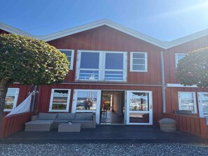 A two-story building with a red exterior, large windows, and a covered outdoor seating area. - 4 Star Holiday Home in Ebeltoft (Ebeltoft)