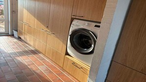 A laundry room with wooden cabinets and a washing machine. - 4 Star Holiday Home in Ebeltoft (Ebeltoft)