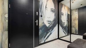 Ein Flur mit einem großen abstrakten Gemälde an der Wand, einer schwarzen Tür und einer Bank.