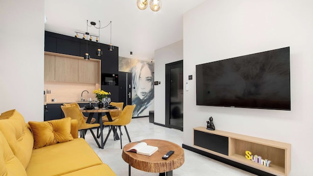 Ein modernes Wohnzimmer mit einer Couch, einem Couchtisch und einem an der Wand befestigten Fernseher.