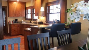 Una cocina con armarios de madera, una isla central y un comedor con sillas y una mesa.