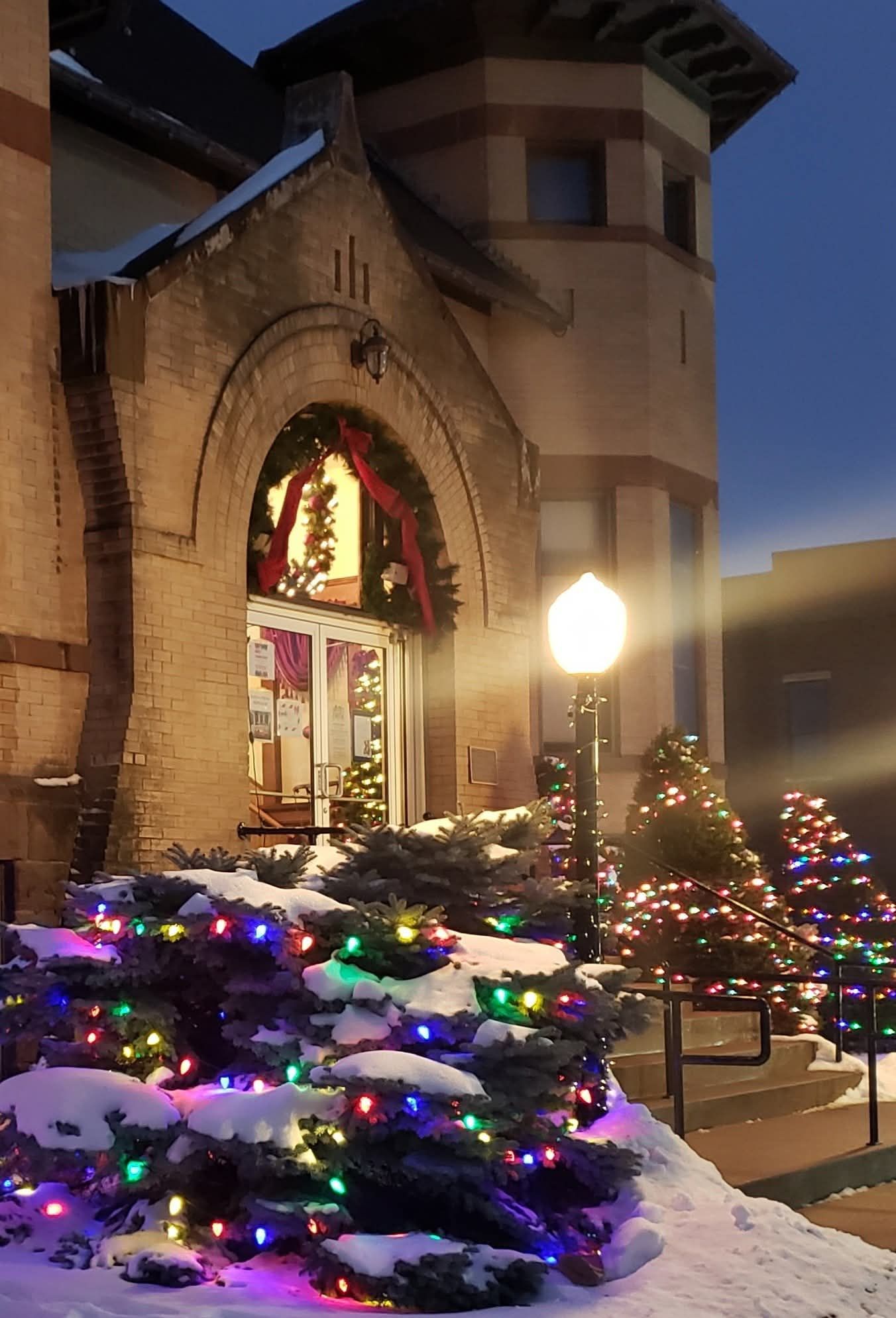 A building with a brick facade, an arched entrance, and a snow-covered ground.