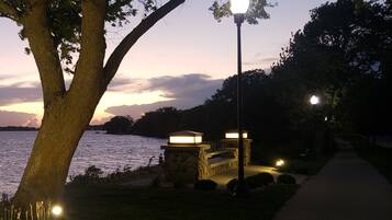 A pathway beside a body of water with a stone structure and a lamp post.