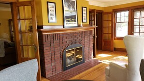 Una habitación con chimenea de ladrillo, una mesa de comedor y un ventanal grande.
