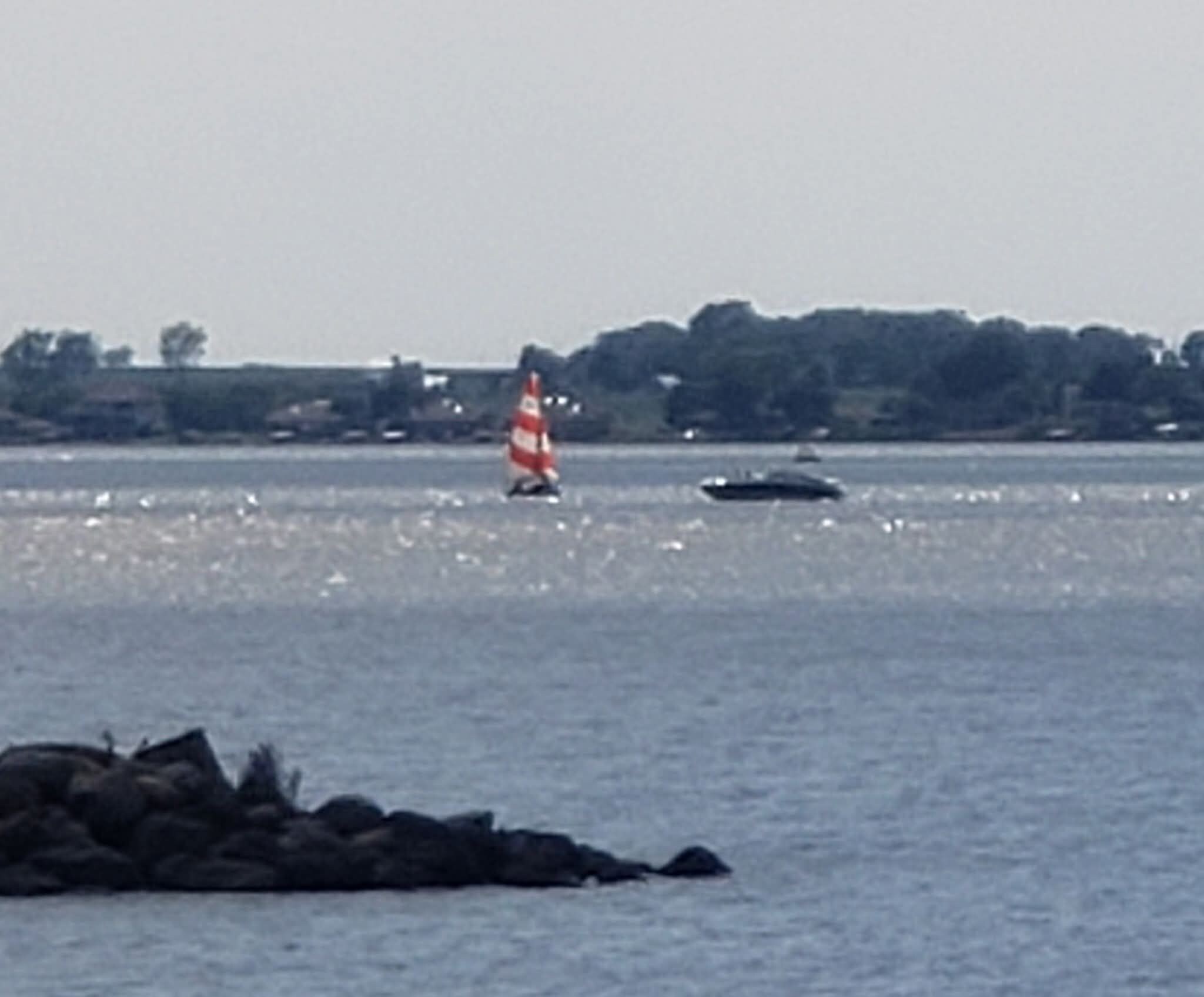 Ein Gewässer mit einem Segelboot und einem Bojen.