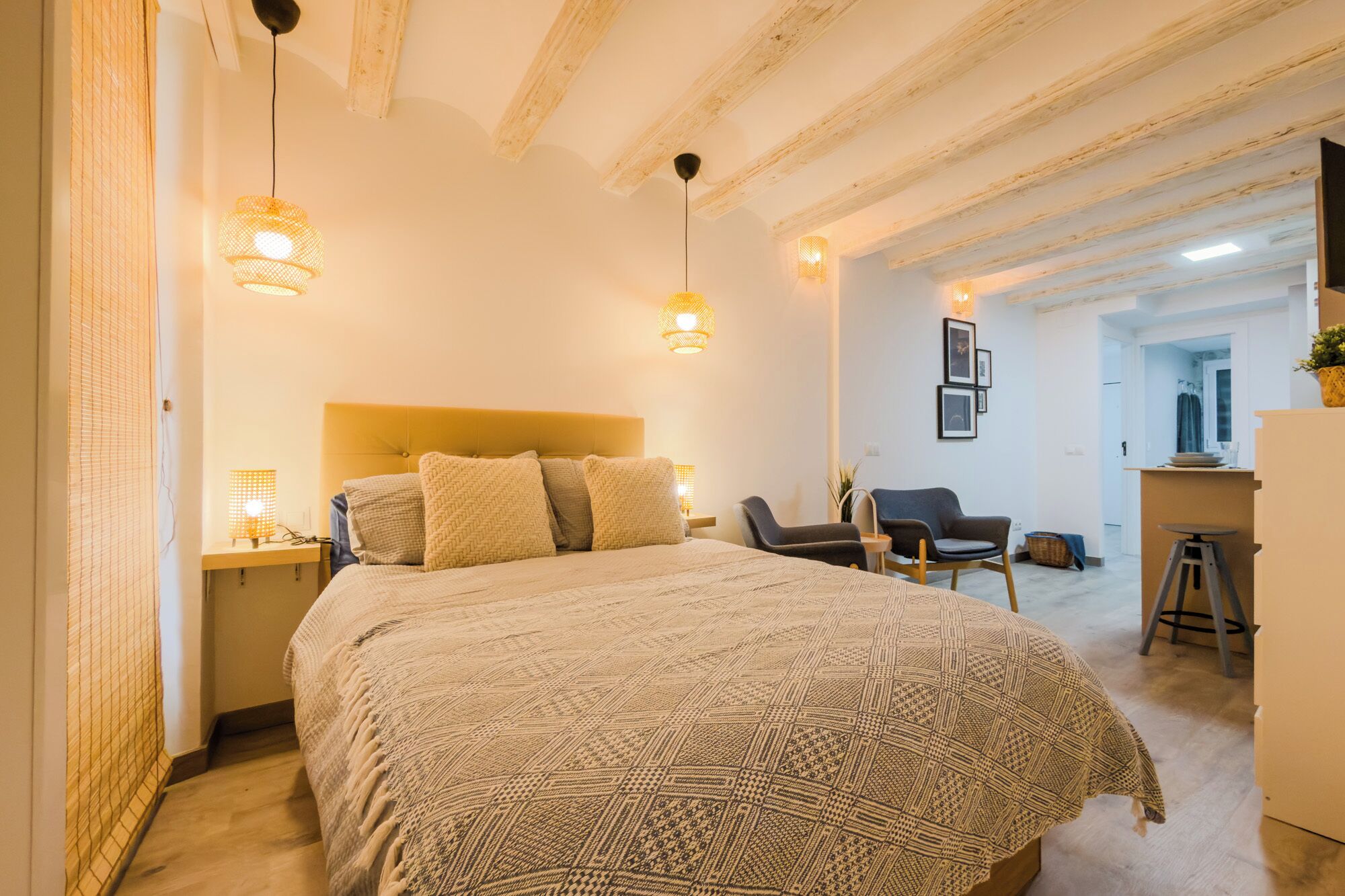 A bedroom with a large bed, two bedside lamps, a headboard, and a chair.