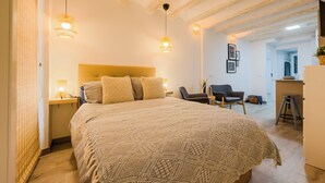 A bedroom with a large bed, two bedside lamps, a headboard, and a chair. - ROBADOR 31 STUDIO 2 (Barcelona)