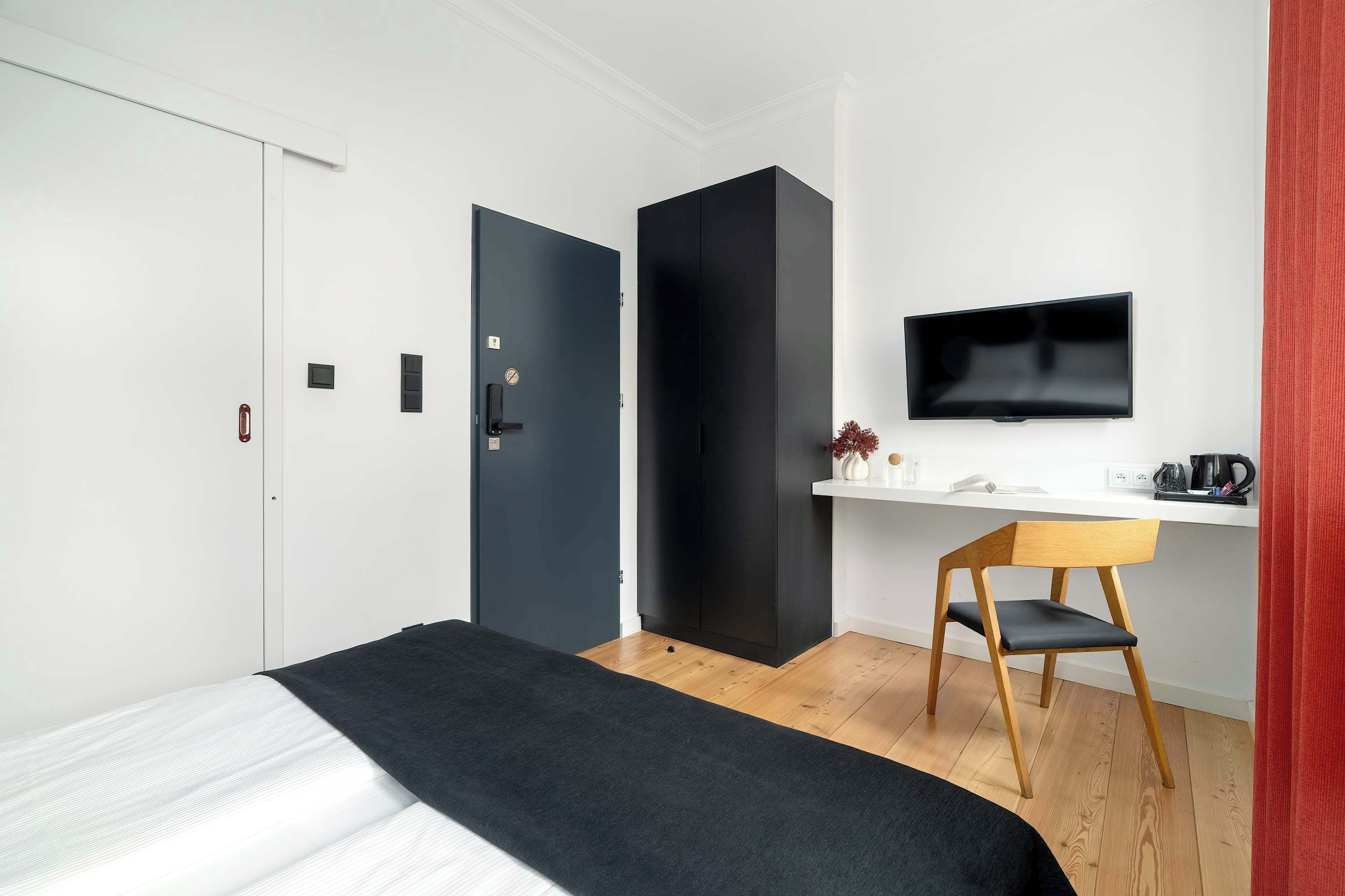 Une chambre à coucher avec un lit, un bureau, une chaise, une télévision et une armoire.