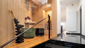 Ein modernes Interieur mit einer Holztreppe, einem schwarzen Marmorboden und einer Holzwand mit einer dekorativen Sonnenschirm-Attrappe.