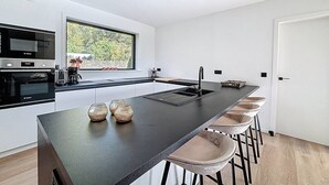 Una cocina moderna con una isla grande, taburetes de bar y un horno empotrado.