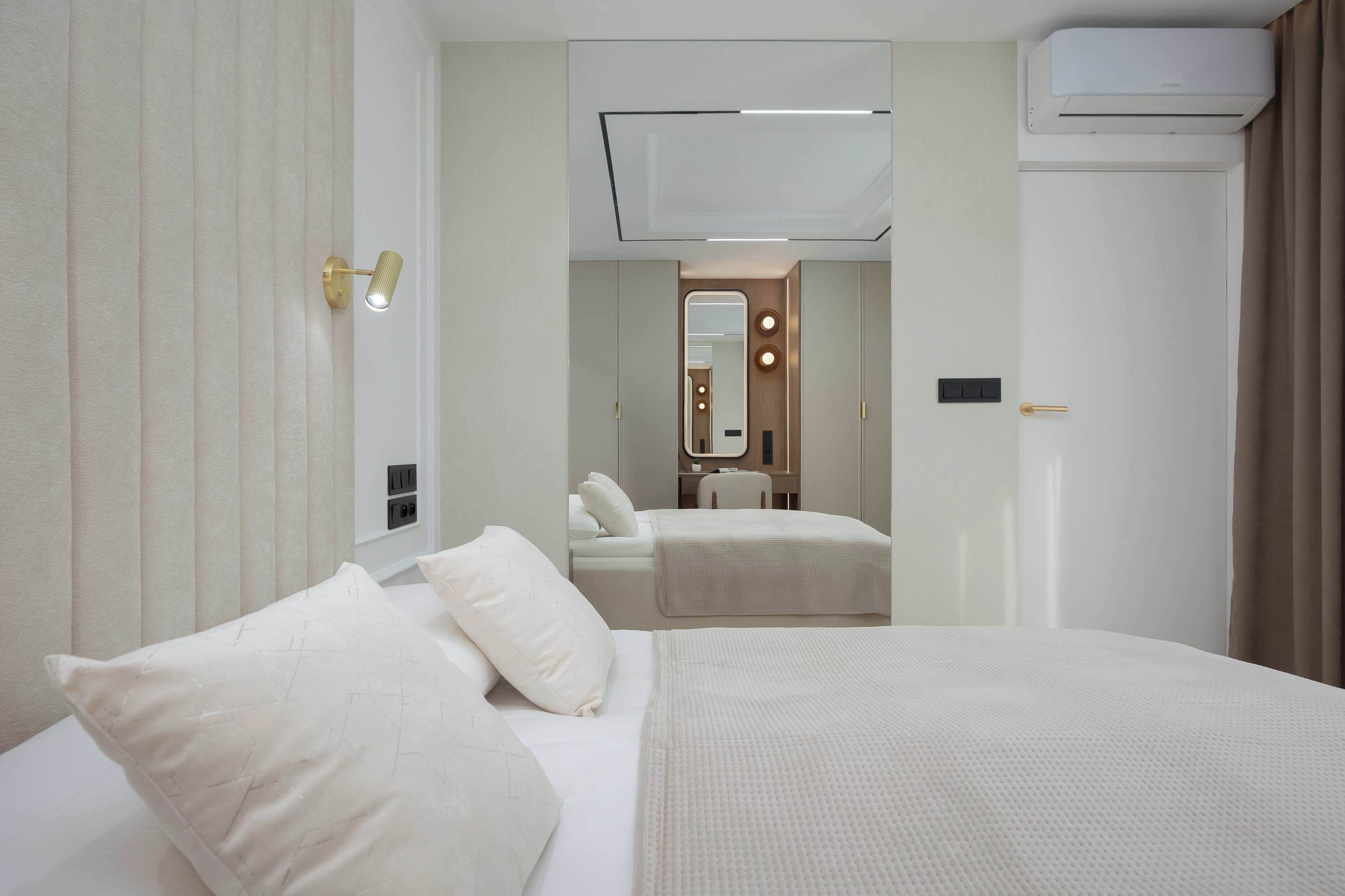 Une chambre d’hôtel avec un lit, des tables de chevet, un miroir et une porte.