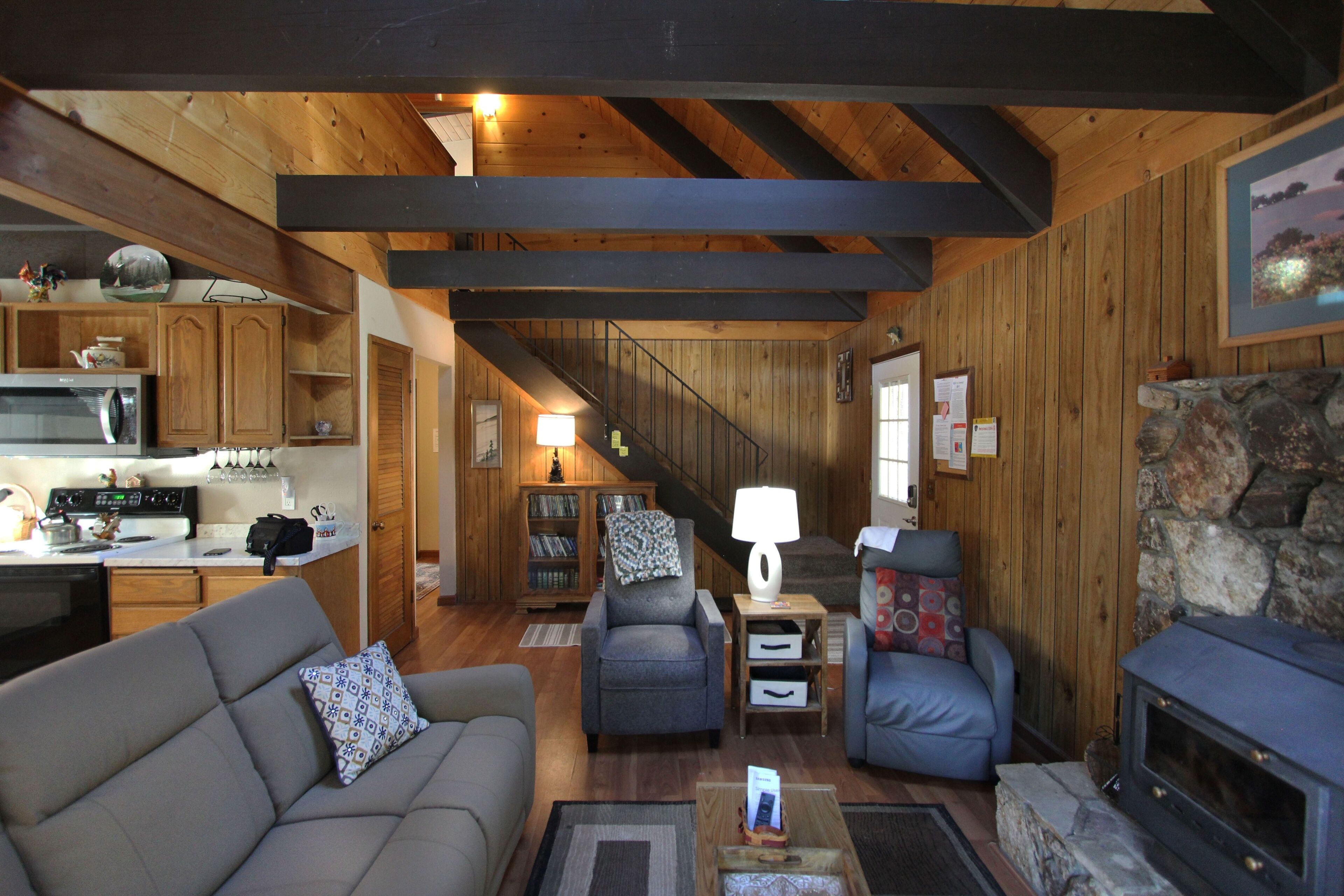 Een gezellig chalet van binnen, met een woonkamer, keuken en open haard.