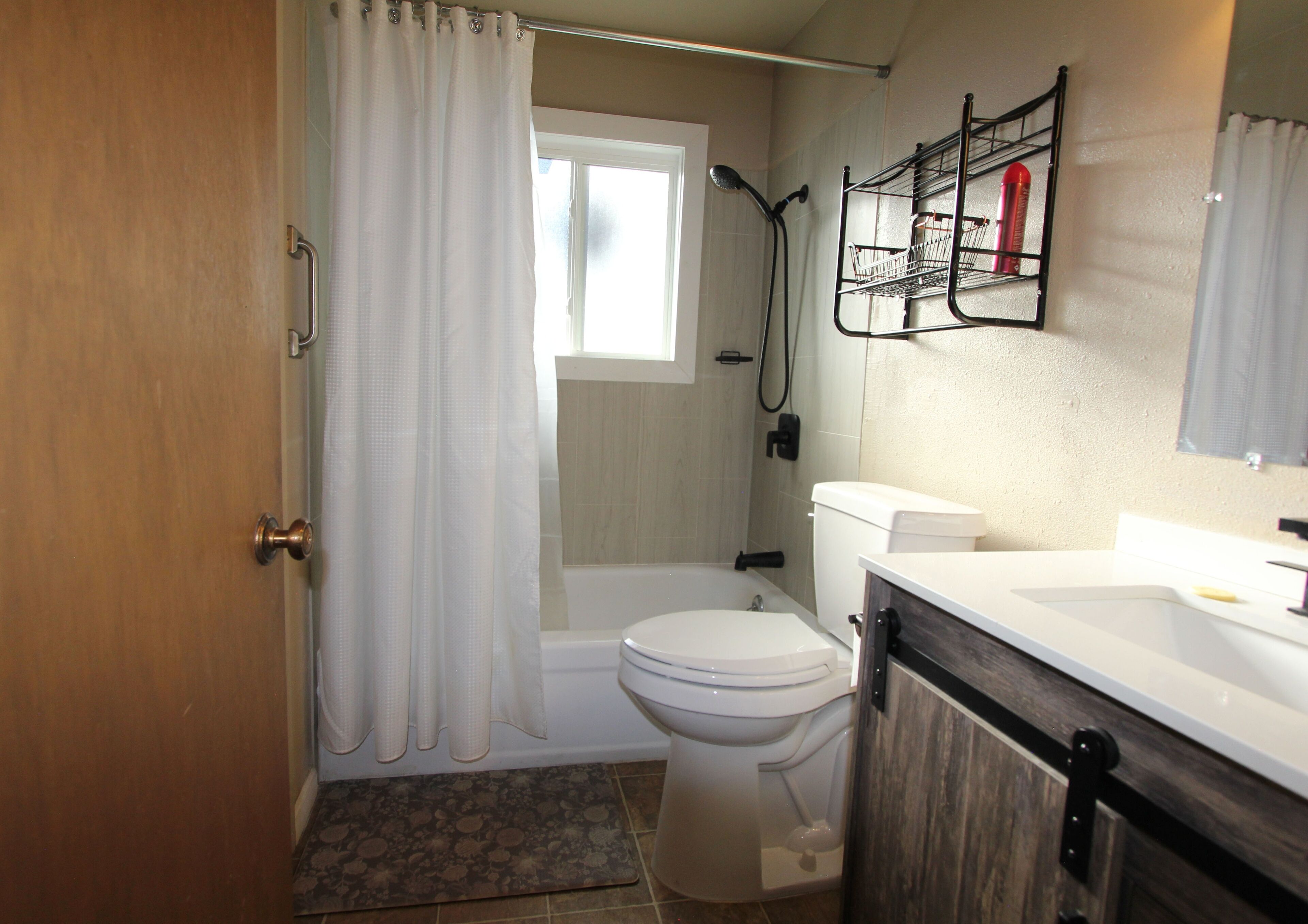 A bathroom with a toilet, shower, and sink.
