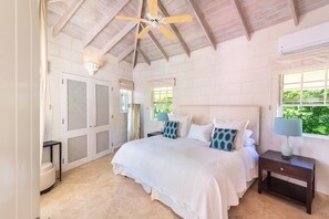 A bedroom with a bed, nightstands, a ceiling fan, a window, and a door with a mesh screen. - Sugar Hill - Half Century House 6 Bedroom Villa (Holetown)
