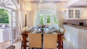 A dining room with a table set for four, a ceiling fan, and a view of greenery outside. - Sugar Hill - Half Century House 6 Bedroom Villa (Holetown)