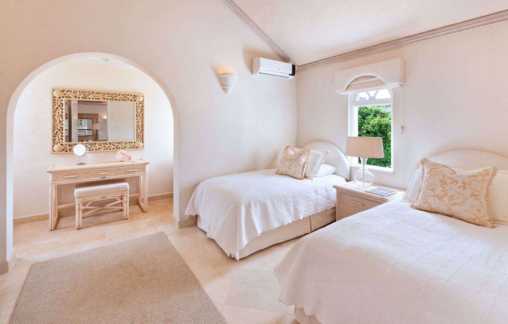 Un dormitorio con dos camas, un tocador con espejo y una ventana con vistas a zonas verdes.