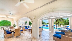 An outdoor patio area with wicker furniture, a pool, and a view of the greenery. - Sugar Hill - Half Century House 6 Bedroom Villa (Holetown)