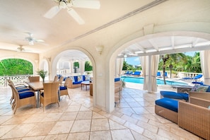 Eine Außenpatio-Terrasse mit Korbmöbeln, einem Pool und Blick ins Grün.