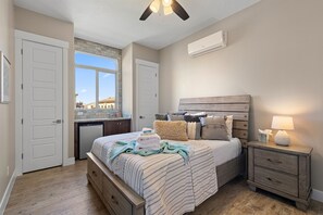 Une chambre à coucher comprenant un lit, des tables de chevet, une commode, une fenêtre et un appareil de climatisation.