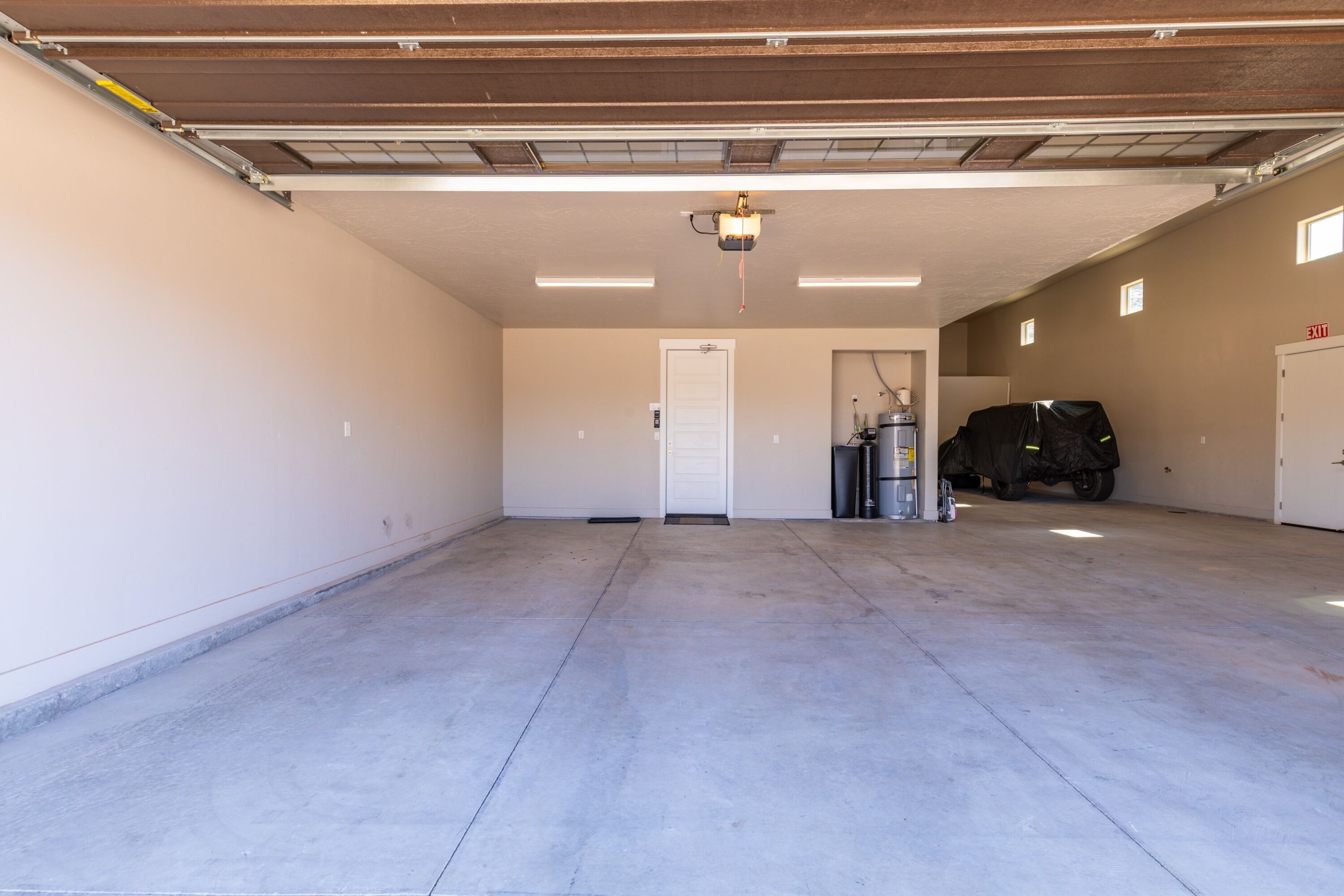 Eine geräumige Garage mit Betonboden, einer weißen Tür und einem überdachten Fahrzeug.