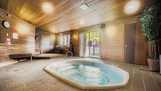 Un intérieur en bois avec un jacuzzi, des bancs et une horloge.
