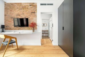 A modern kitchen with a brick wall, a flat-screen TV, and a wooden chair. - Stylish Studio at the Market | Air Conditioning and Workspace (Poznań)