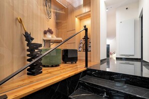 A modern interior with a wooden staircase, a black marble floor, and a wooden wall with a decorative umbrella.