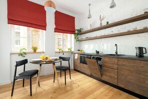 A modern kitchen with wooden cabinets, a black countertop, and a dining area with two black chairs.