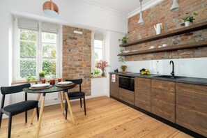 A kitchen with a brick wall, wooden cabinets, and a dining area with a table and chairs.